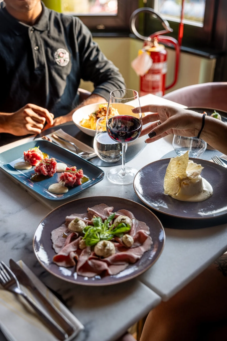 Tavolo con piatti e un calice di vino rosso